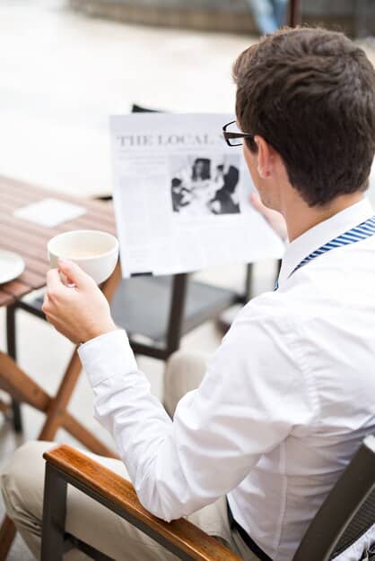 Close-up of a casting director reviewing headshots and resumes in a brightly lit office. The director is focused with a pen in hand, highlighting notes on a document. Shelves behind are filled with scripts and casting reference materials.