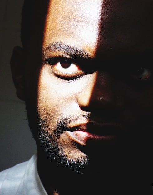 A close-up shot of an actor portraying a character in an intense, introspective scene. The lighting is dramatic, emphasizing the emotional weight of the moment. The backdrop is blurred, focusing attention on the actor's expression.