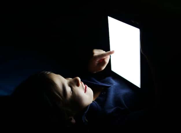 A close-up of a person's captivated face lit by the glow of a tablet screen in a darkened room, highlighting the immersive nature of binge-watching.