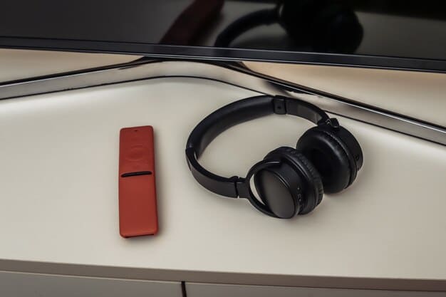 A detailed shot of high-quality headphones resting on a remote control next to a laptop displaying a streaming series, emphasizing the importance of sound and device quality for an immersive experience.