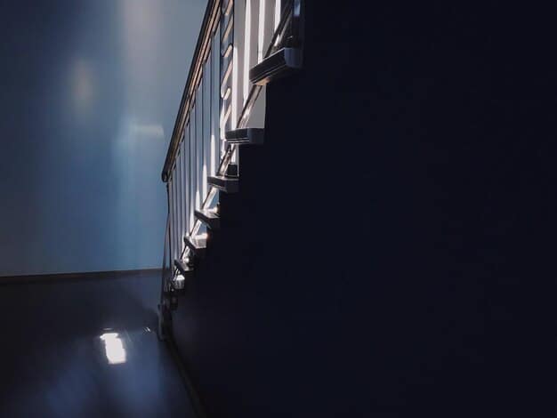 A dark, narrow staircase leading downwards into an ominous, dimly lit basement, with subtle shadows suggesting unseen presence.