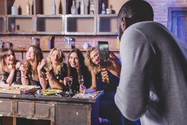 A diverse group of people sitting around a large screen, clearly engrossed in a show, with snacks and drinks scattered around, depicting a communal binge-watching experience.