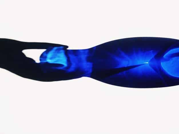 A dramatic, overhead shot of a holographic representation of Cortana, her blue light flickering with a hint of red, superimposed over Master Chief's hand, suggesting her continued influence or a lingering connection.