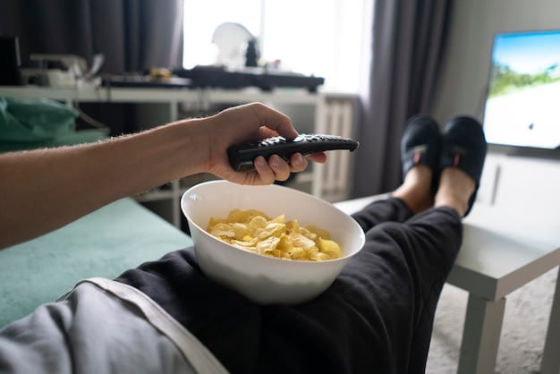A close-up shot of a TV remote resting on a couch with a half-eaten bowl of popcorn in the background. The TV screen in the distance shows a cliffhanger scene from a popular drama series, symbolizing the irresistible urge to continue watching. The question 'Is' being visually answered through details.