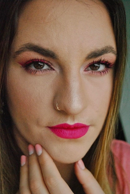 A close up of a woman's eye, showcasing a soft pink eyeshadow look with subtle shimmer, a thin brown eyeliner, curled lashes, and a delicately highlighted aegyo sal (under-eye pouch). It emphasizes the application techniques required to achieve K-Drama Makeup Secrets: Achieve the vibrant eye look.
