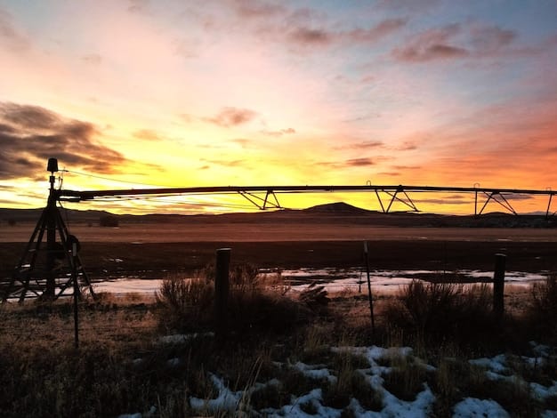 A landscape image of the Yellowstone ranch at sunset, with a dramatic sky in the background. The ranch house is visible in the distance, and the scene is filled with a sense of peace and foreboding. Captures the spirit of 'Yellowstone' Season 5, Part 2: Kevin Costner's Exit.