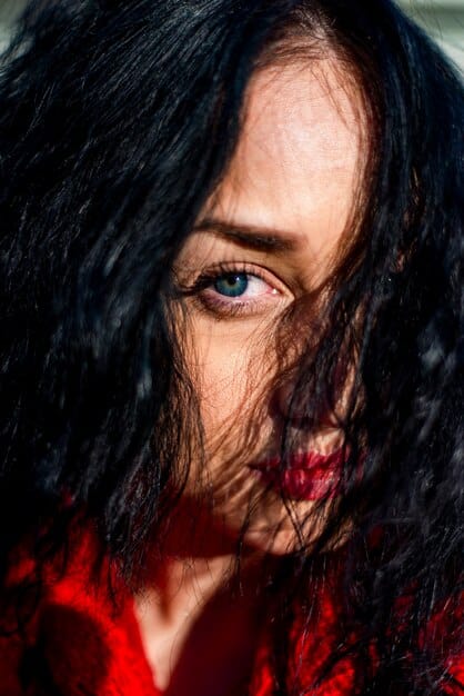 A close-up portrait of Rhaenyra Targaryen, her expression a mix of determination and worry. She is seated at a table in a dimly lit room, studying a large, open book. Her hand rests on a page filled with ancient High Valyrian script. Soft candlelight illuminates her face, highlighting the weight of her responsibilities and the looming threat of war from 'House of the Dragon' Season 2.
